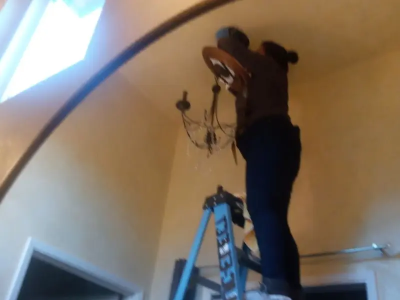 Electrician installing a chandelier in a Attalla residence